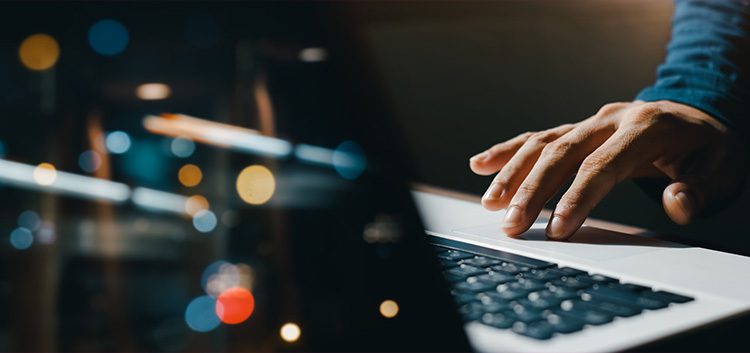 Hand die een laptoptoetsenbord aanraakt.