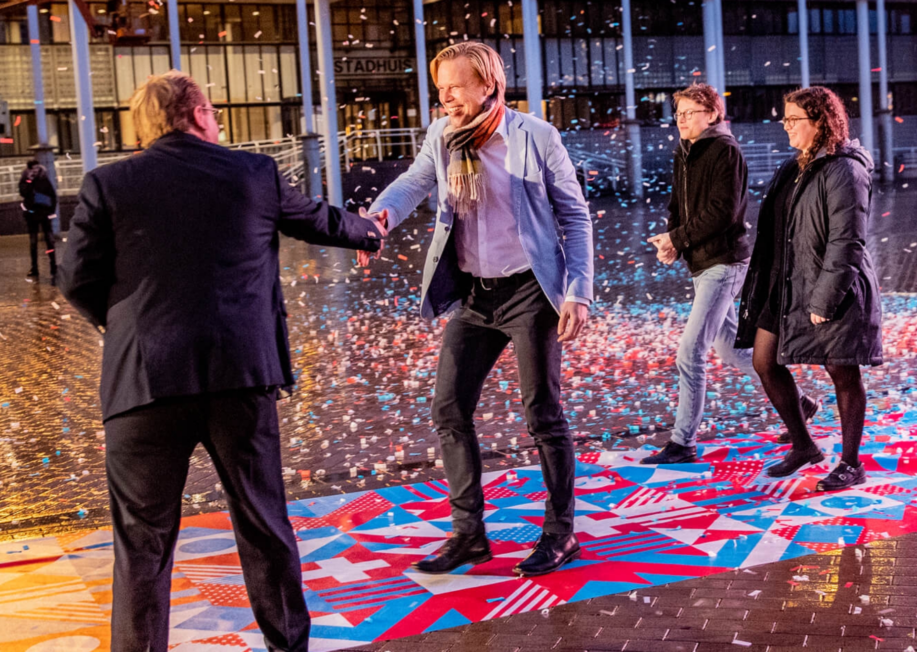 Mensen schudden handen op het Marktplein in Apeldoorn tijdens de campagne voor de herinrichting van het plein.