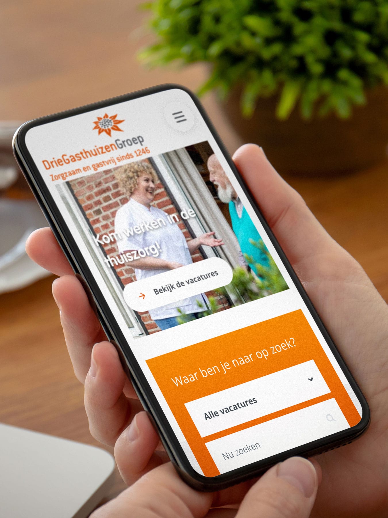 Smartphone met DrieGasthuizenGroep website op het scherm.
