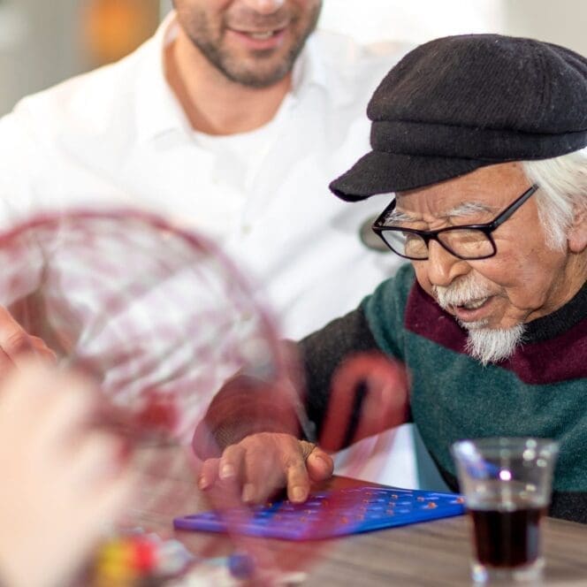 Oudere man speelt bingo met begeleider.