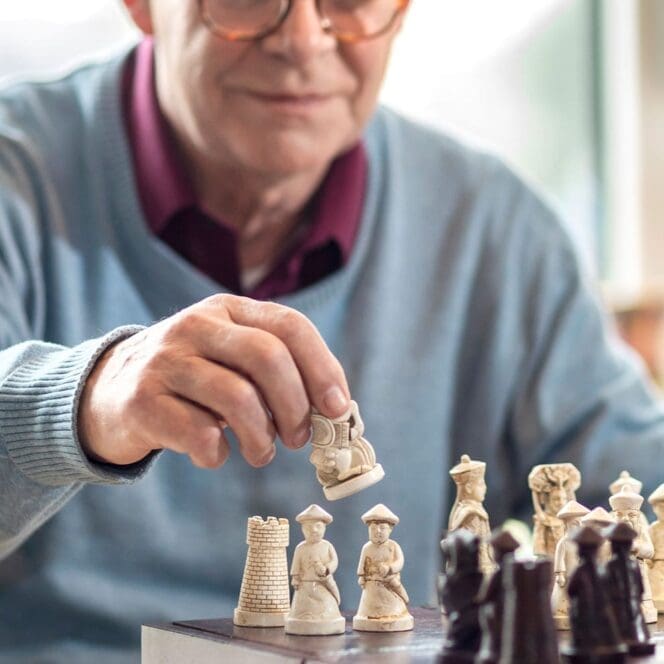 Oudere man speelt schaak met stenen schaakstukken.