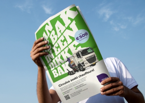 Persoon houdt krantadvertentie vast met tekst 'Aan de bak in een dikke bak'.