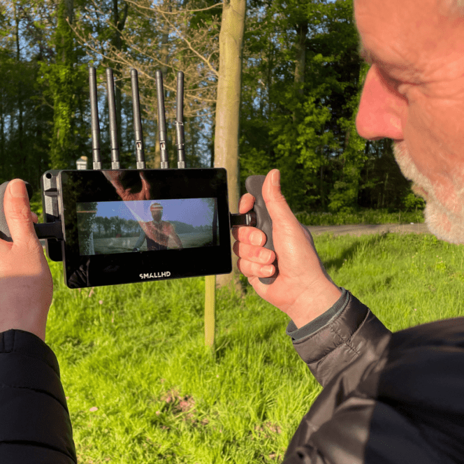 Man bekijkt opname op monitor tijdens filmopname in natuur.