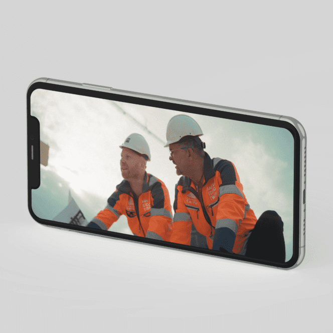 Twee bouwvakkers in oranje werkkleding op een smartphone scherm.