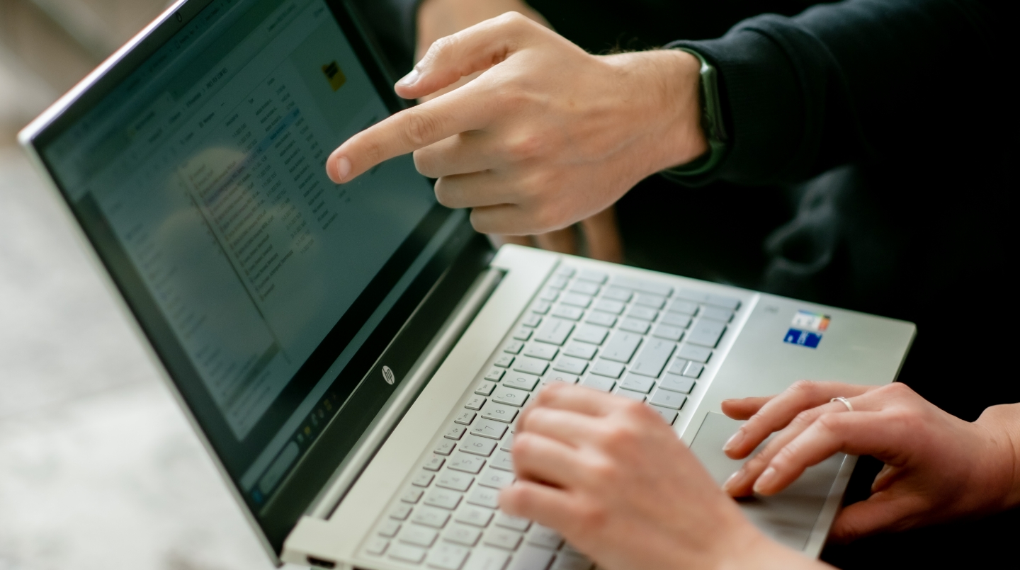 Twee personen werken samen achter een laptop.