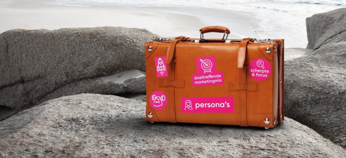 Koffer met marketing- en persona-iconen op rotsen bij zee.