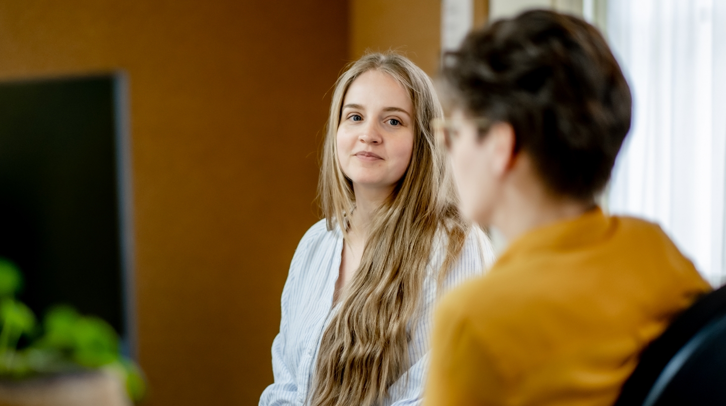 Twee mensen in gesprek in een kantooromgeving.