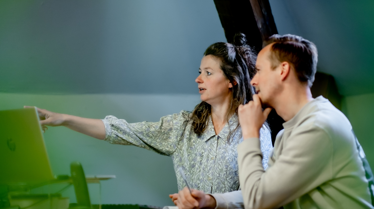 Twee mensen werken samen aan een project op een computer.
