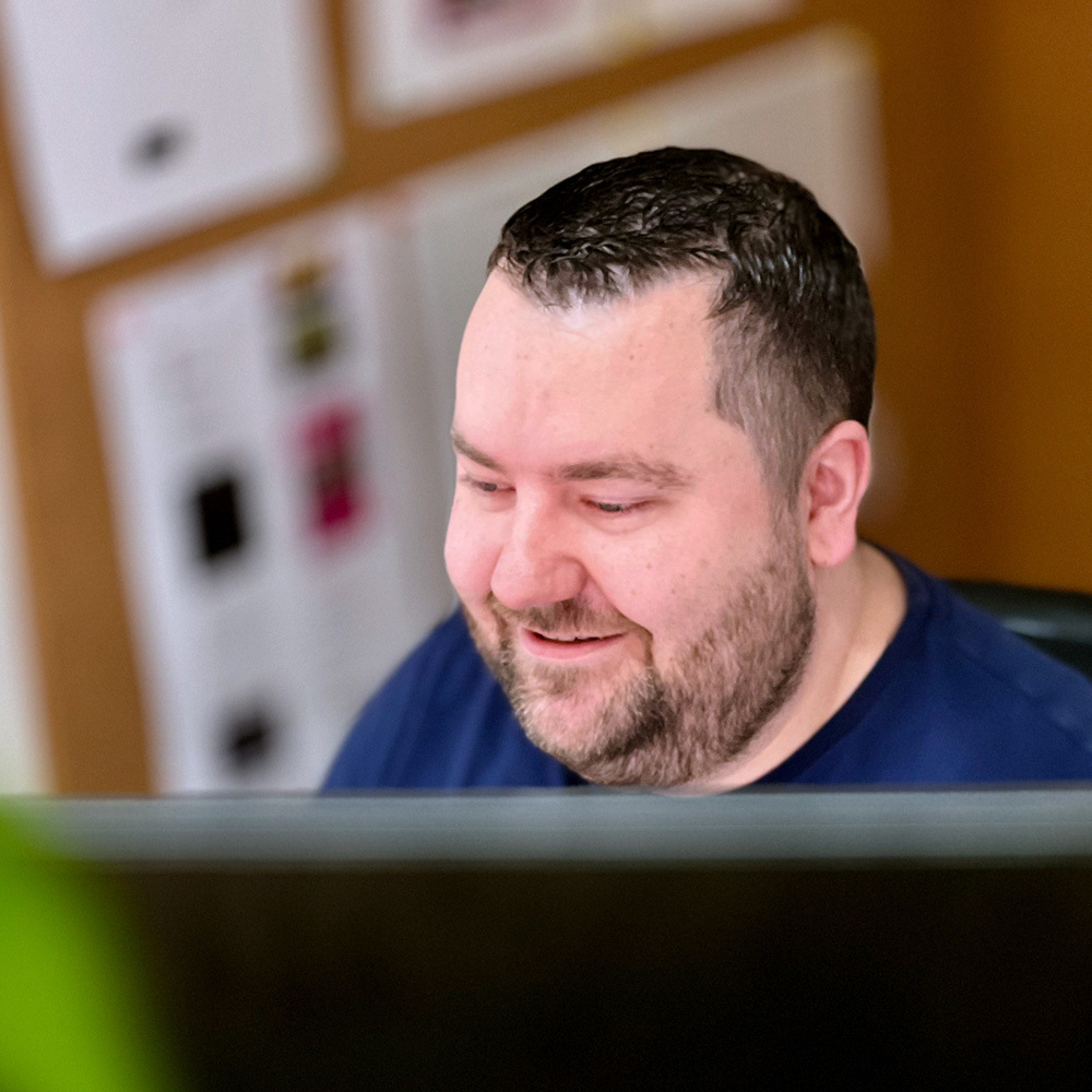 Marco kijkt glimlachend naar computerscherm.