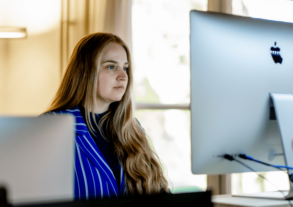 Irne werkt geconcentreerd achter een iMac-computer.