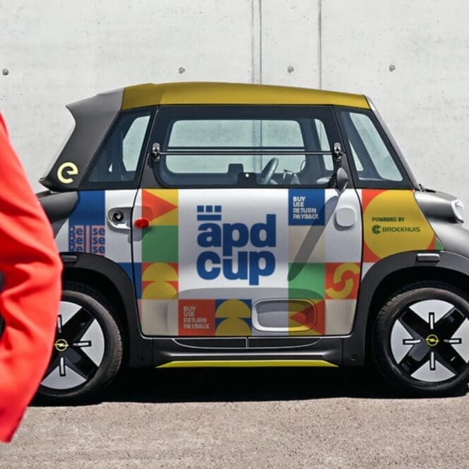 Kleine elektrische auto met kleurrijke APD-CUP branding en logo, ingezet voor het circulaire bekersysteem bij evenementen in Apeldoorn.