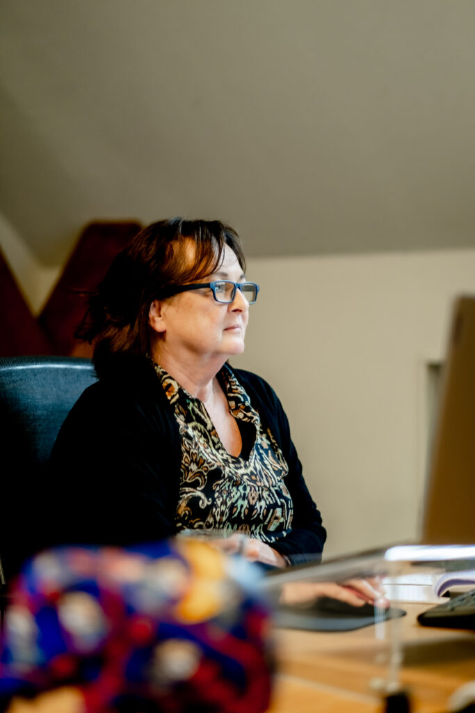 Anita zit aan een bureau en kijkt naar een computerscherm.